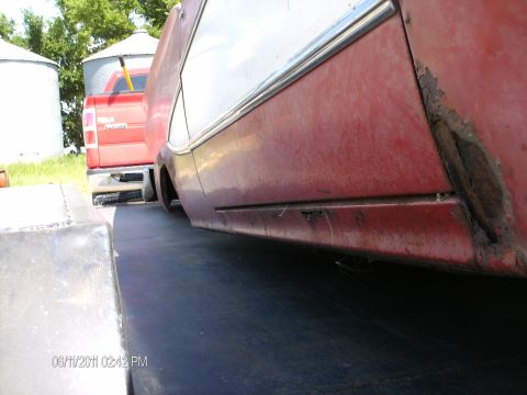 1958 Ford Fairlane - Side view of a red car's lower body panel, showing significant rust and damage.