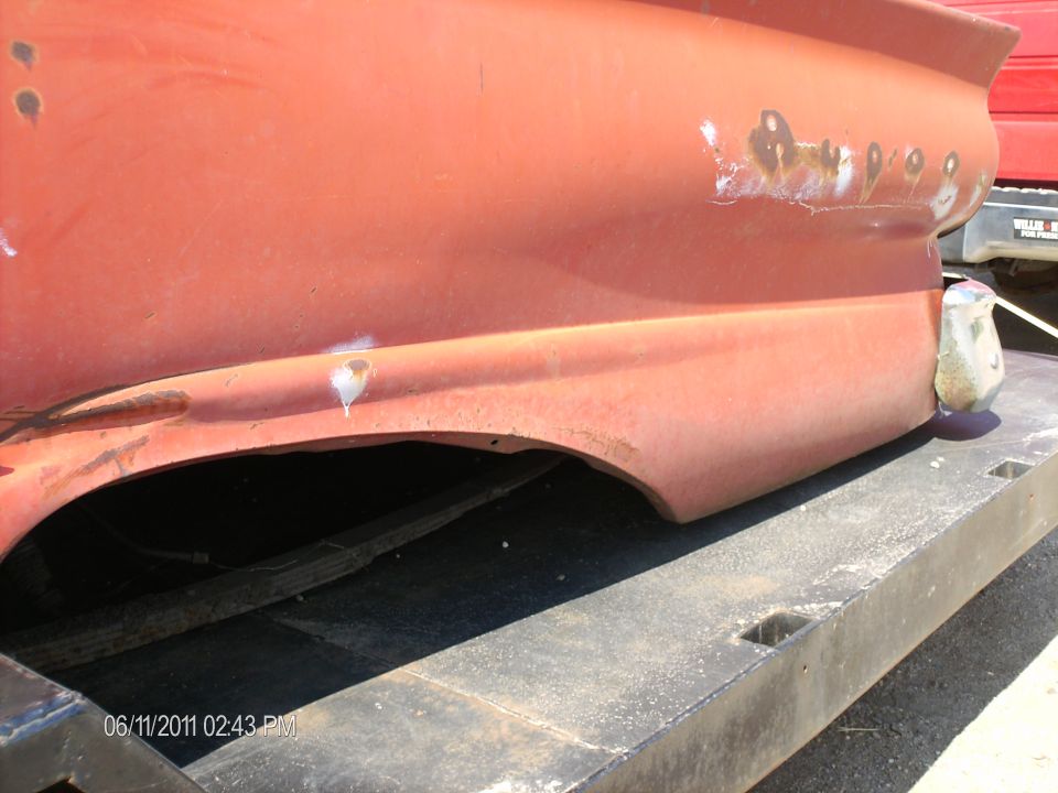 close-up of rusty orange rear fender and quarter panel of a car on a trailer