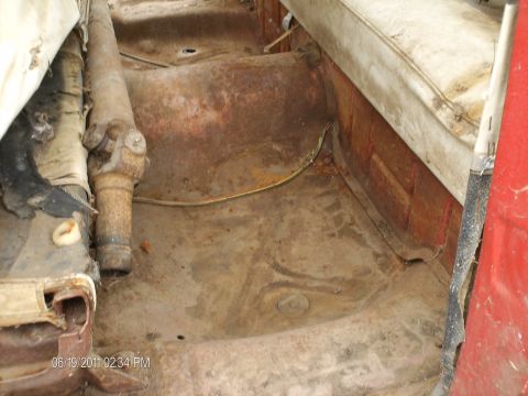 1958 Ford Fairlane - The interior floor and driveshaft of a vehicle exhibit extensive rust and deterioration, indicating a need for restoration.