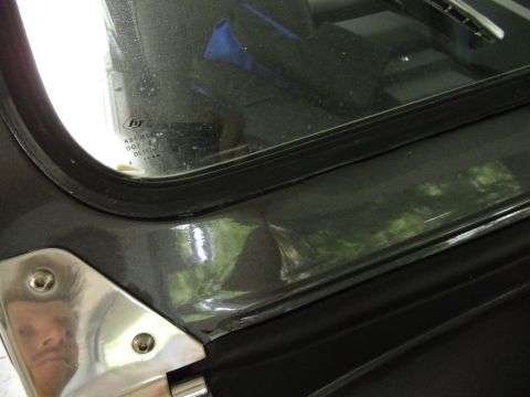 1978 Ford Bronco - Detail of a vehicle's door frame and window, with a reflection in the chrome trim.