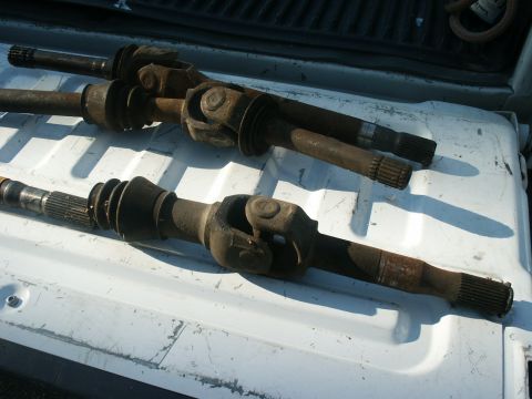 1990 Ford Bronco - Two old drive shafts are resting on a white surface, likely in the bed of a truck.