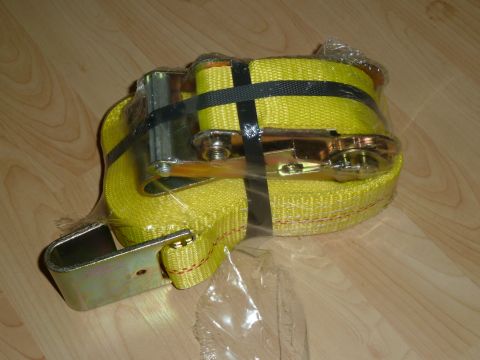 1992 Ford Mustang - A yellow ratchet tie-down strap is shown on a wooden surface, secured with black straps and wrapped in clear plastic.