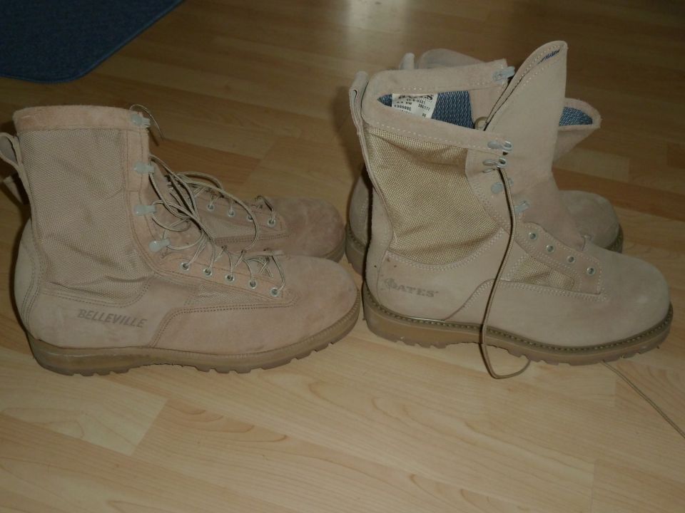 two pairs of tan combat boots, one Belleville and one Bates, on a wooden floor