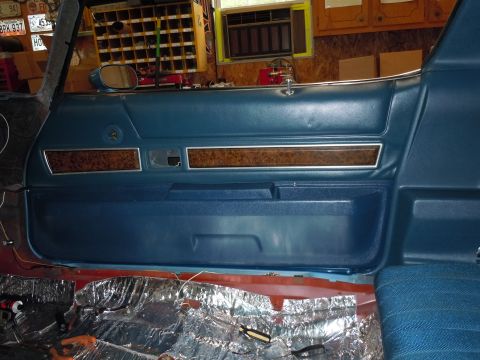 1972 Chevrolet Camaro - The interior of a car shows a blue door panel with woodgrain accents and insulation laid out on the floor.