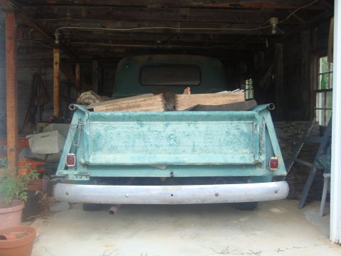 2002 Chevrolet Silverado 1500 - Rear view of a teal pickup truck parked inside a wooden structure, carrying lumber in its bed.