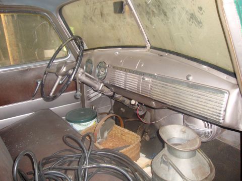 2002 Chevrolet Silverado 1500 - The interior of an older vehicle shows a dashboard with gauges and a steering wheel, with various items stored inside.