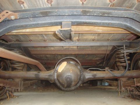 2002 Chevrolet Silverado 1500 - The rear axle and leaf spring suspension system of a vintage pickup truck is visible from below.