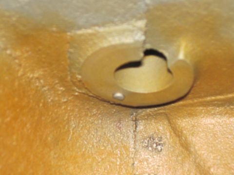 1979 Ford Bronco - A close-up view of an engine component, showing a circular recess and a metallic pin. The surface has a textured, aged appearance.