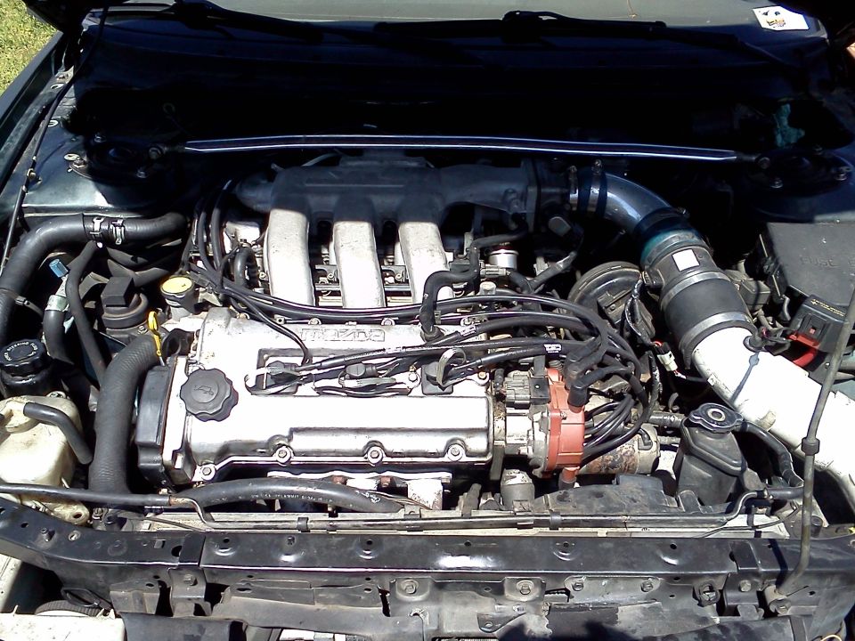 Mazda four-cylinder engine bay with polished cam cover and black intake tube