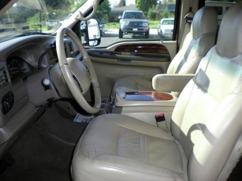2000 Ford Excursion - The interior of a 2000 Ford Excursion features tan leather seats and wood trim accents, with other vehicles visible outside.