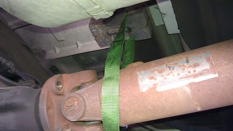 2000 Ford Excursion - Vehicle driveshaft and U-joint assembly shown with a green strap. Text on the driveshaft is partially obscured.