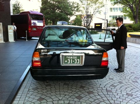 2010 Ford Falcon - A black sedan taxi is parked on a cobblestone driveway, with a man in a suit opening the passenger door.