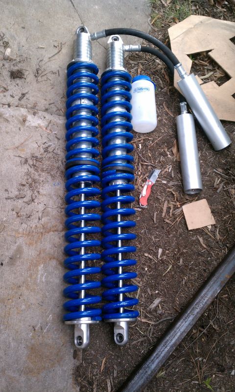 1990 Ford Bronco - Pair of blue coilover shock absorbers and associated parts laid out on the ground.