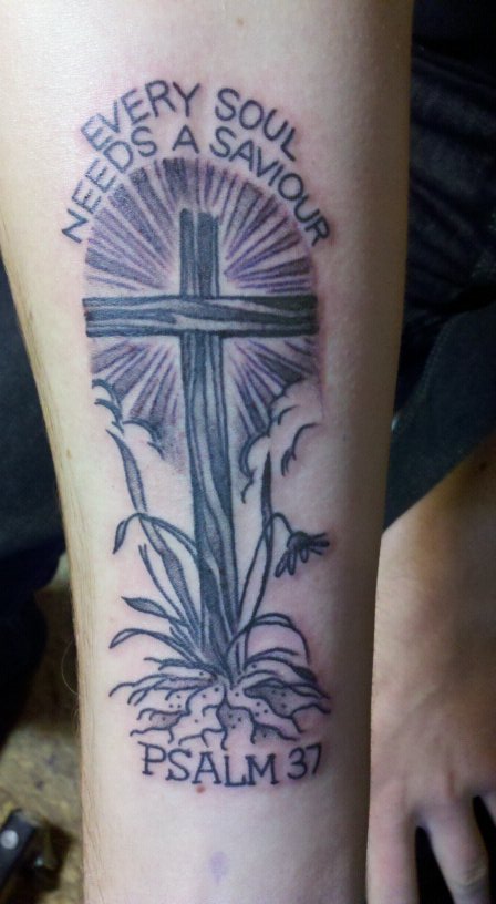 1989 Ford Bronco - A tattoo depicts a cross with radiating light, surrounded by plants and inscribed with religious text.