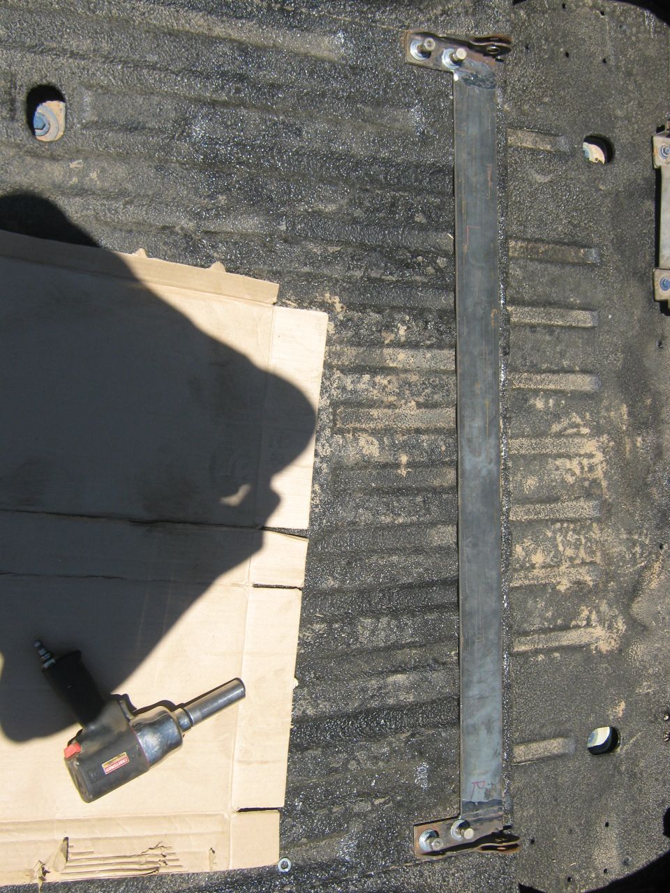 Metal bar and impact wrench on textured truck bed floor