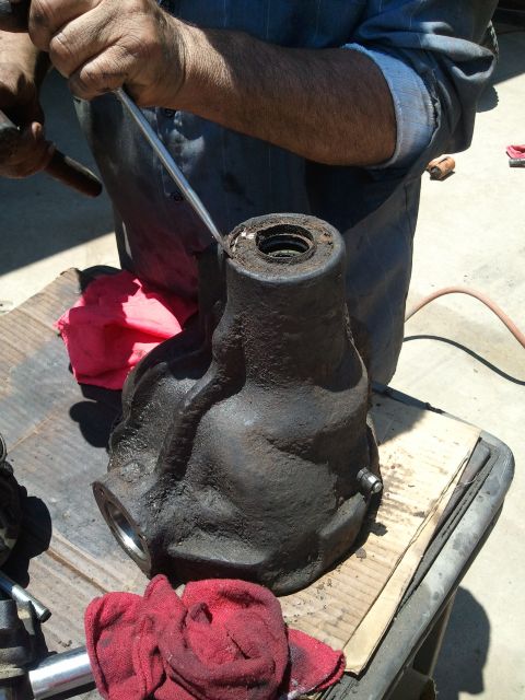 1982 Ford Bronco - A mechanic works on a greasy differential housing, likely during a gear installation or repair.
