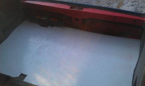 1991 Ford Festiva - The interior of a car trunk is shown with a white liner and red painted metal.
