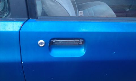 1991 Ford Festiva - Close-up of a blue car's exterior door handle and lock mechanism.