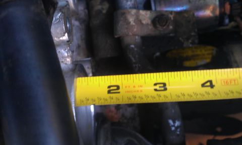 1991 Ford Festiva - Close-up of engine parts with a measuring tape indicating dimensions.