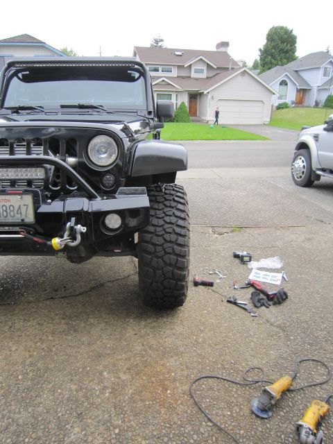 2008 Jeep Wrangler - A black Jeep Wrangler is parked in a driveway with tools scattered nearby, while a silver truck is visible in the background.