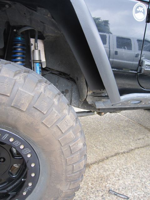 2008 Jeep Wrangler - Tight front wheel-well shot of a dark Jeep Wrangler showing a blue-spring coilover with a remote-reservoir off-road racing shock, a black b…