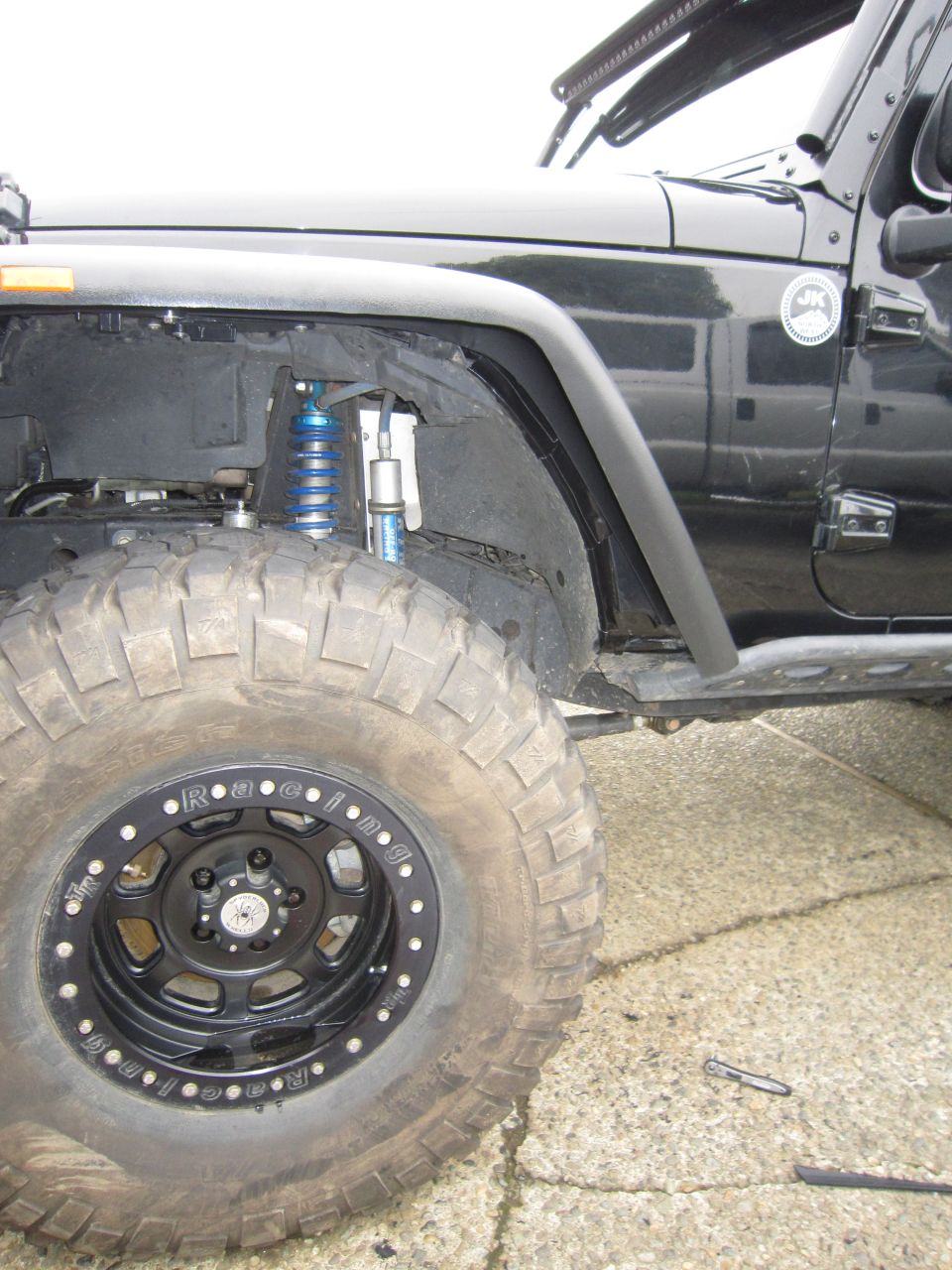 Black Jeep Wrangler JK front suspension with blue coilover, beadlock wheel and mud tire