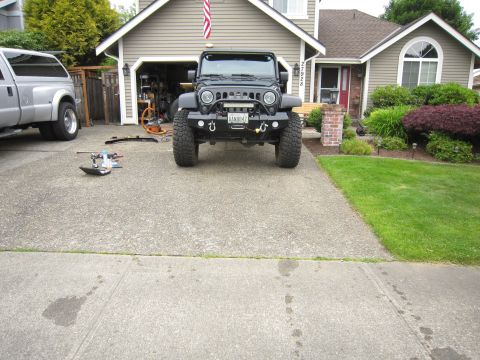 2008 Jeep Wrangler - Head-on front view of a lifted black Jeep Wrangler parked in a suburban driveway, wearing a black steel stubby front bumper with D-ring sha…
