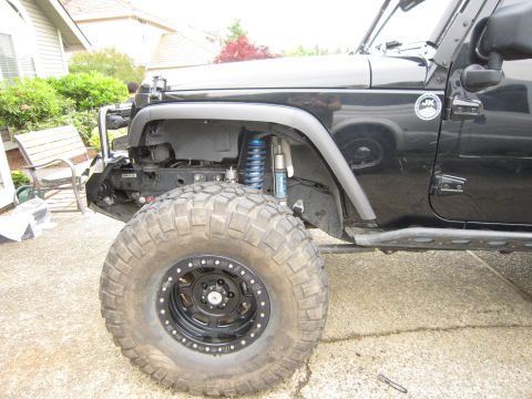 2008 Jeep Wrangler - Front quarter of a black Jeep Wrangler JK on a driveway with the front fender flare and inner liner exposed, showing a blue-spring coilover…