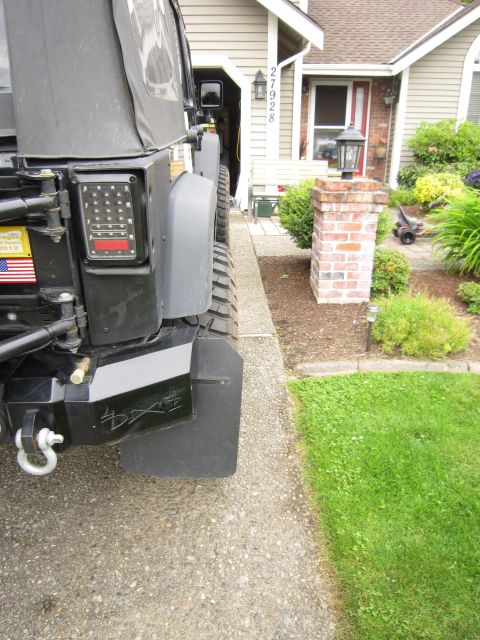 2008 Jeep Wrangler - Rear corner detail of a black soft-top Jeep Wrangler parked on a residential driveway, showing a heavy steel rear bumper with a D-ring shac…