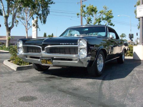 2007 Ford Mustang - A classic black Pontiac Tempest is parked in a lot on a sunny day.