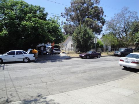 2003 Ford Taurus - Several vehicles are parked on a residential street with their hoods open.