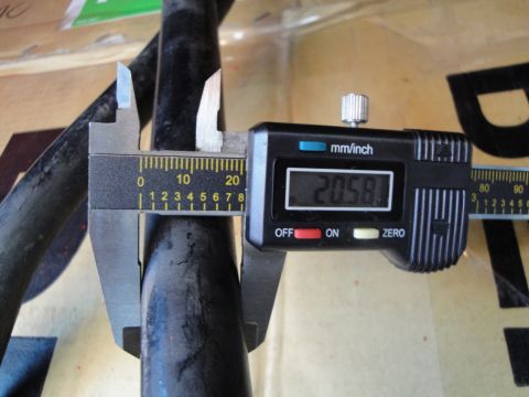 2003 Ford Taurus - A close-up shows digital calipers measuring the diameter of a black pipe, indicating 20.58 mm.