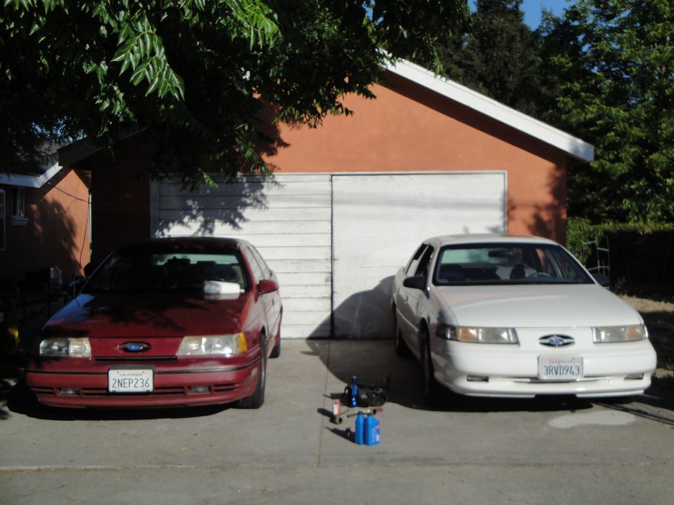 1992 Ford Taurus (red) and 1996 Ford Taurus (white) parked in front of garage