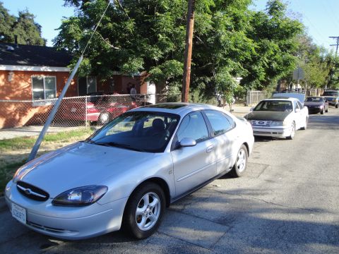 2003 Ford Taurus - Silver 2003 Ford Taurus parked on a residential street with other vehicles in the background.