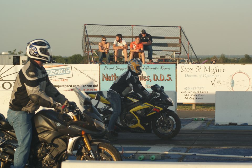 Two motorcycles at a drag strip, one yellow and black, the other dark colored
