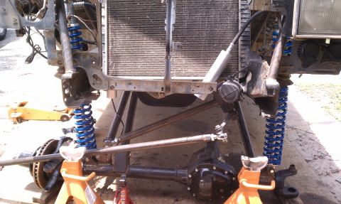 1990 Ford Bronco - Front axle and suspension components are visible, supported by jack stands with a radiator behind.