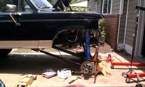 1990 Ford Bronco - Front suspension of a black 1990 Ford Bronco is disassembled, revealing the frame and suspension components.