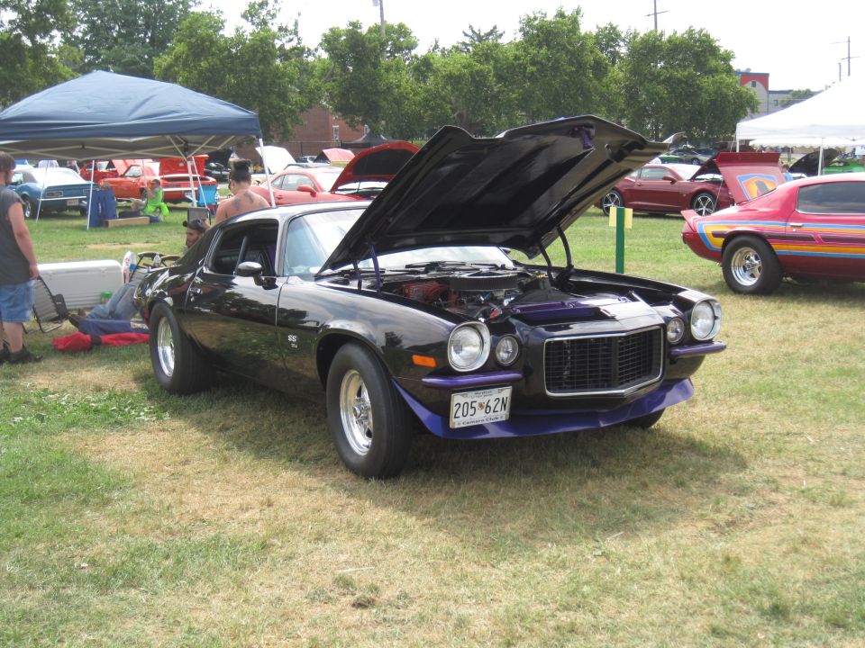 Black Chevrolet Camaro with purple front splitter and hood accents, hood open, showing engine. License plate reads 205-62N