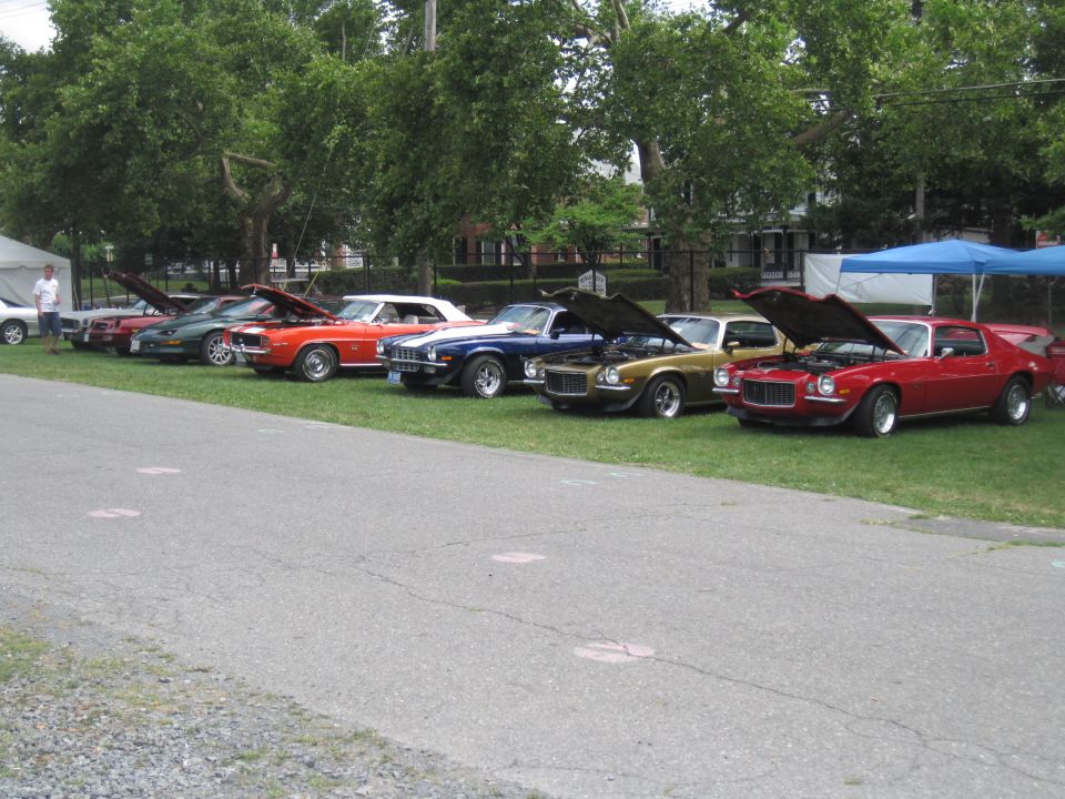Red 1970s Chevrolet Camaro parked on grass with hood open