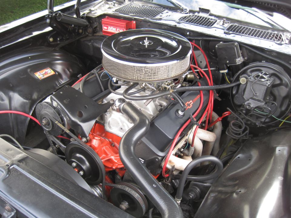 Black engine bay with a V8 engine, chrome air cleaner, and red Chevrolet valve covers