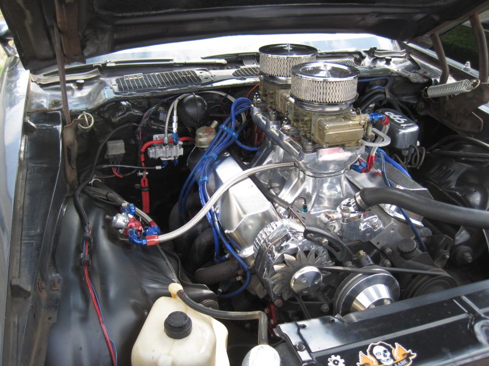 Engine bay with dual carburetors, chrome air cleaners, and blue spark plug wires