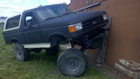1988 Ford Bronco - This lifted 1988 Ford Bronco is parked with its front end leaning against a building.