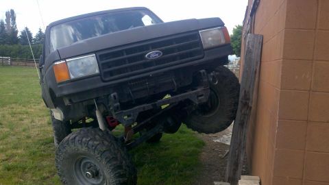 1988 Ford Bronco - Modified 1987 Ford Bronco with off-road tires is positioned against a building.