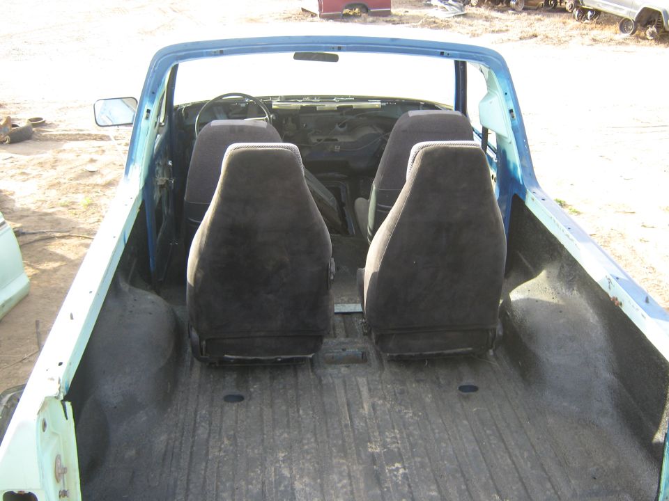 Interior view of a blue pickup truck with four dark seats and a bare dashboard