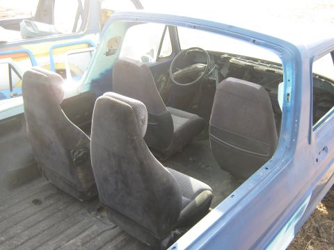 1978 Ford Bronco - The interior of a blue vehicle shows four seats and a dashboard, with another vehicle in the background.