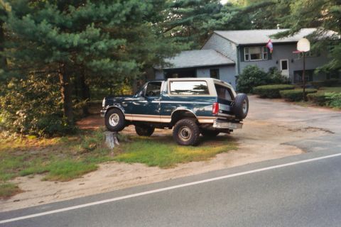 1994 Ford Bronco - This 1994 Ford Bronco is seen parked on a dirt incline next to a house and trees.