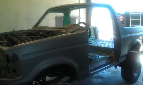 1995 Ford Bronco - This 1995 Ford Bronco is in primer with its doors open and interior stripped, suggesting it is undergoing restoration.