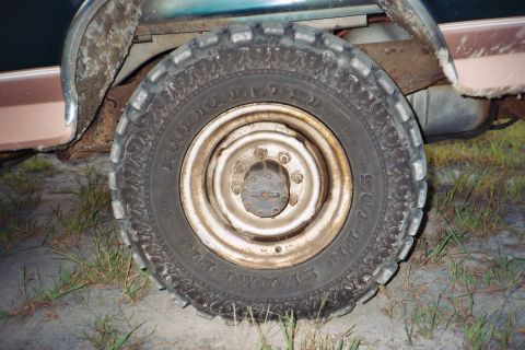 1994 Ford Bronco - A close-up view of a vehicle's tire and wheel, showing signs of wear and rust.