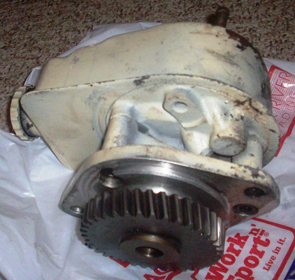 Used off-white cast aluminum pump assembly with exposed helical drive gear and mounting flange