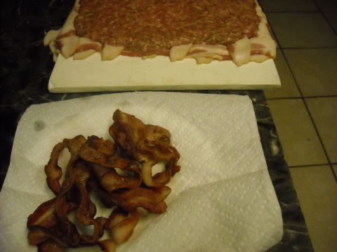 1979 Ford F-150 - A meatloaf wrapped in bacon sits on a cutting board next to a pile of fried bacon on paper towels.